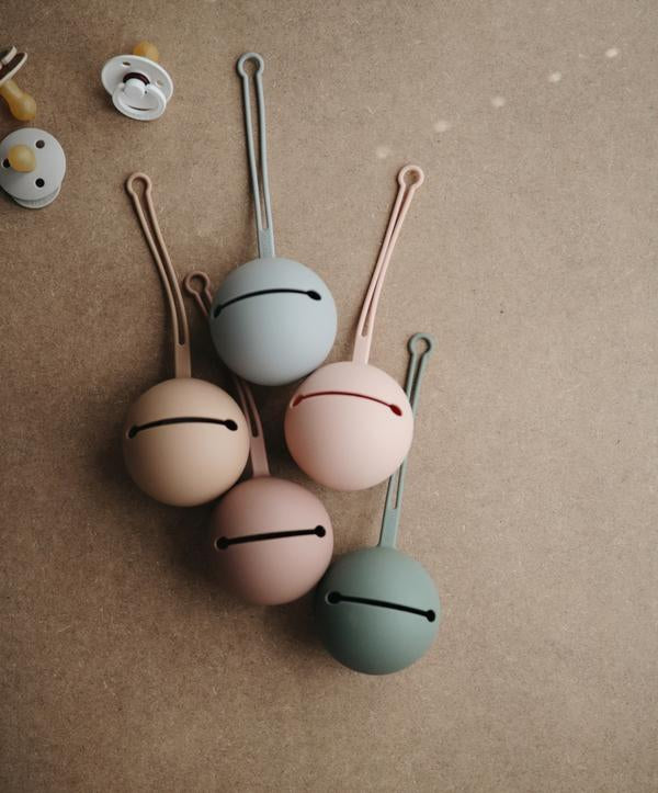 Mushie Dummy Case in blush, durable BPA-free silicone design, holds up to 3 dummies with a convenient strap for on-the-go storage.